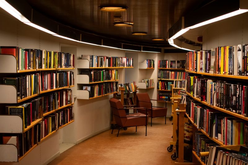Estantería de madera con libros antiguos y luz natural entrando por una ventana lateral